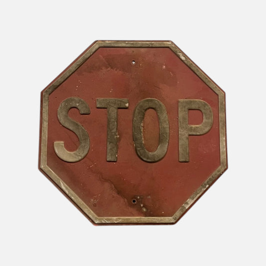 Weathered octagonal stop sign, faded red with raised STOP letters and a raised border worn to bare metal, on a white background.